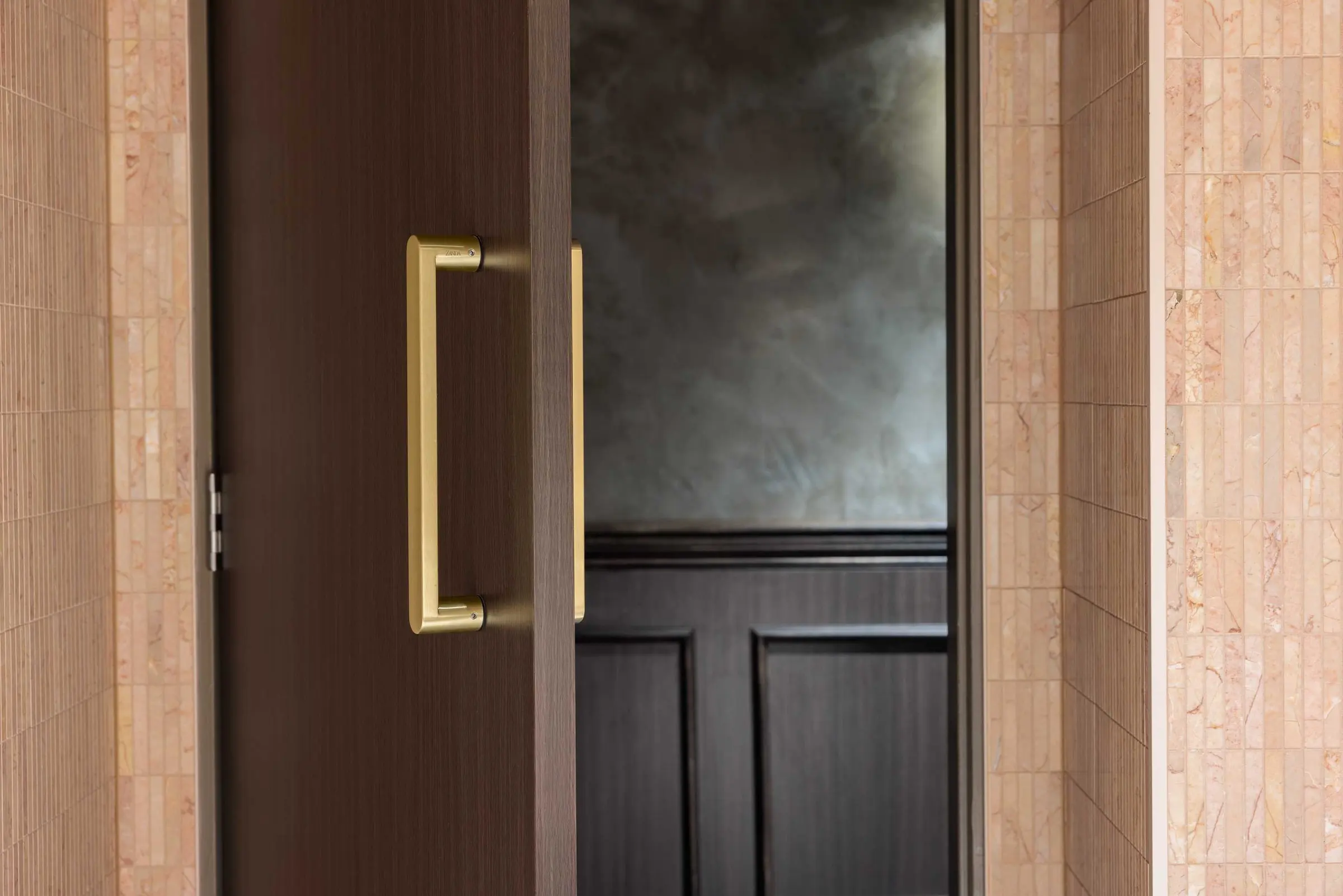 Zanda Duke pull handle in Satin Brass on a dark timber entrance door